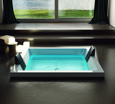 an indoor hot tub in front of a window with the view of water and grass