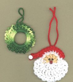 two crocheted christmas ornaments hanging on a gray wall next to a green wreath