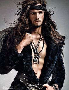 a shirtless man with long hair and no shirt wearing a leather belt is posing for the camera