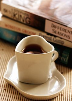 a coffee cup sitting on top of a saucer next to some books and a book