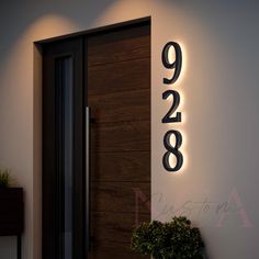 a modern house number sign mounted to the side of a door with lights on it