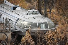 an abandoned train car sitting in the middle of some trees with yellow leaves on it