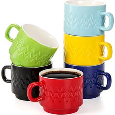 four different colored coffee mugs sitting next to each other on a white surface with one cup in the middle