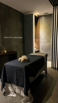 a massage table with towels on it in a room that has black and white walls