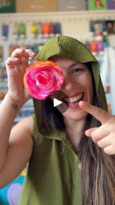 a woman in a green hoodie pointing at a pink donut