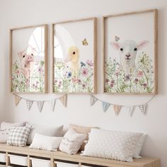 three framed pictures hang on the wall above a wooden bench with pillows and blankets underneath them