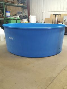 a large blue swimming pool sitting on top of a cement floor in a warehouse area