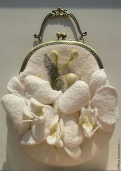 a white purse with flowers on it sitting on top of a table next to a wall