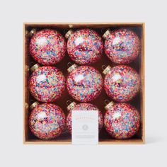 a wooden box filled with red and pink christmas baubles covered in sprinkles