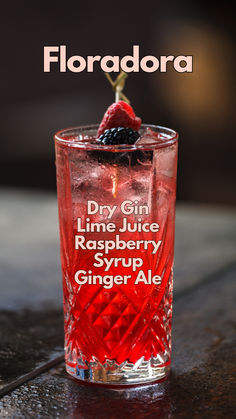 a close up of a glass on a table with a raspberry in it