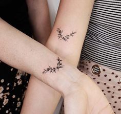 two women with matching tattoos on their arms, both holding each other's hands