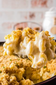 a spoon full of macaroni and cheese being lifted from a casserole dish