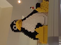 a penguin made out of legos sitting on top of a shelf in a room