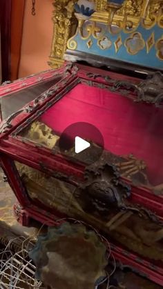 an old trunk is sitting on the floor in front of a gold and red chair