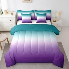 a bed with purple and blue comforters in a room next to a white dresser