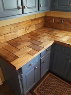 a kitchen counter made out of wood with blue cabinets and drawers on each side, along with a brown door mat