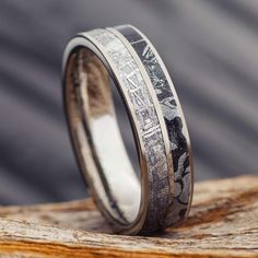 two wedding bands with silver and black wood inlays on top of each other