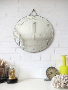 a white brick wall with a round mirror hanging on it's side next to other decorative items