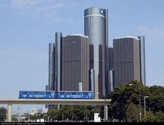 a blue train is on the tracks in front of some tall buildings with skyscrapers