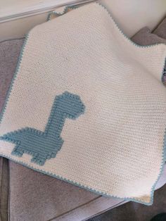 a crocheted blanket with a blue dinosaur on it