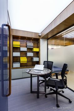 an office with glass walls and desks in the center, along with yellow bookshelves