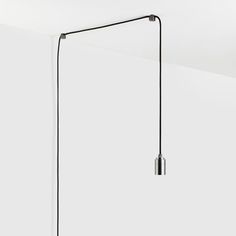 a black floor lamp hanging from the ceiling in a room with white walls and floors