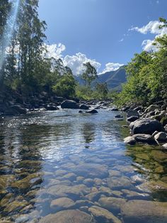 the water is crystal clear and there are rocks on the bank in front of it