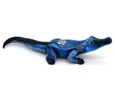 a blue lizard figurine sitting on top of a white surface with an intricate design