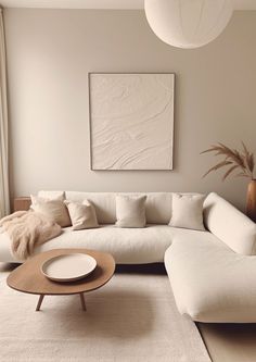 a living room with a large white couch and coffee table in front of a painting on the wall