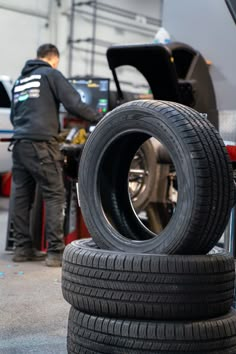 two tires stacked on top of each other in front of a man working on the car