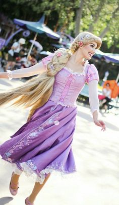 a woman in a purple dress is dancing with long blonde hair and pink shoes on