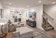 a living room filled with furniture and a flat screen tv mounted on a wall above a fireplace