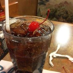 a drink with ice and a cherry on the top sitting on a table next to a toothbrush