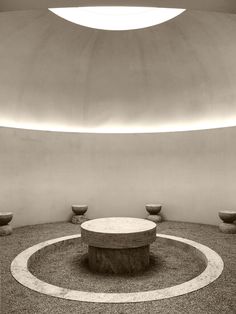 a circular room with two tables and three bowls on the floor in black and white