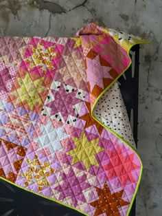 a pink and yellow quilt is hanging on the wall