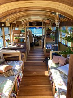 the inside of a bus with wooden flooring and windows on both sides is filled with furniture