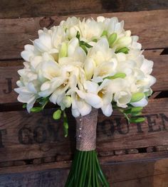 a bouquet of white flowers sitting on top of a wooden bench