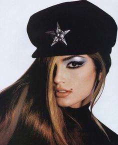 a woman with long hair wearing a black hat and star brooch on her head