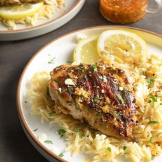 two plates with chicken, rice and lemon slices