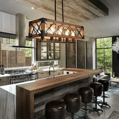 a kitchen with an island, bar stools and chandelier hanging from the ceiling