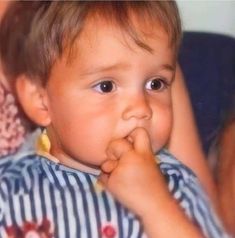 a little boy that is holding something in his hand and looking at the camera while sitting down