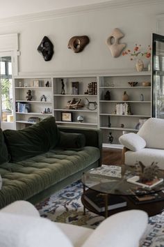 a living room filled with white furniture and lots of bookshelves on the wall