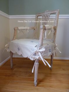 an old chair with white linen tied to it's back and seat cover on top