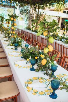 a long table is set up with blue and yellow plates, lemons and greenery