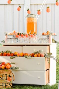 an orange themed party with peaches and cream on the table, in front of a white fence