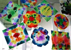 several different colored paper flowers hanging from a window