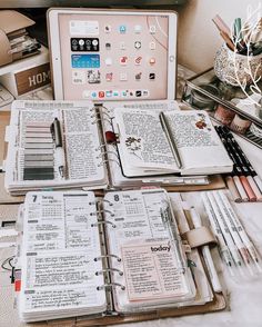 an open book sitting on top of a desk next to a laptop computer and many other items