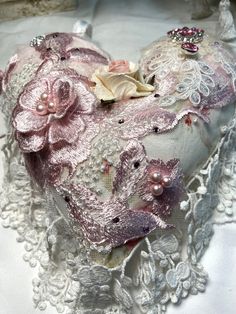 a heart shaped pillow with flowers and pearls