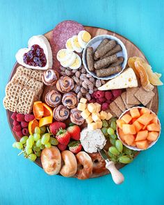 a platter filled with meats, fruit and crackers on a blue table