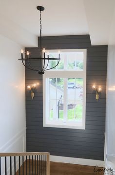 a chandelier hanging from the ceiling in a room with gray walls and white trim